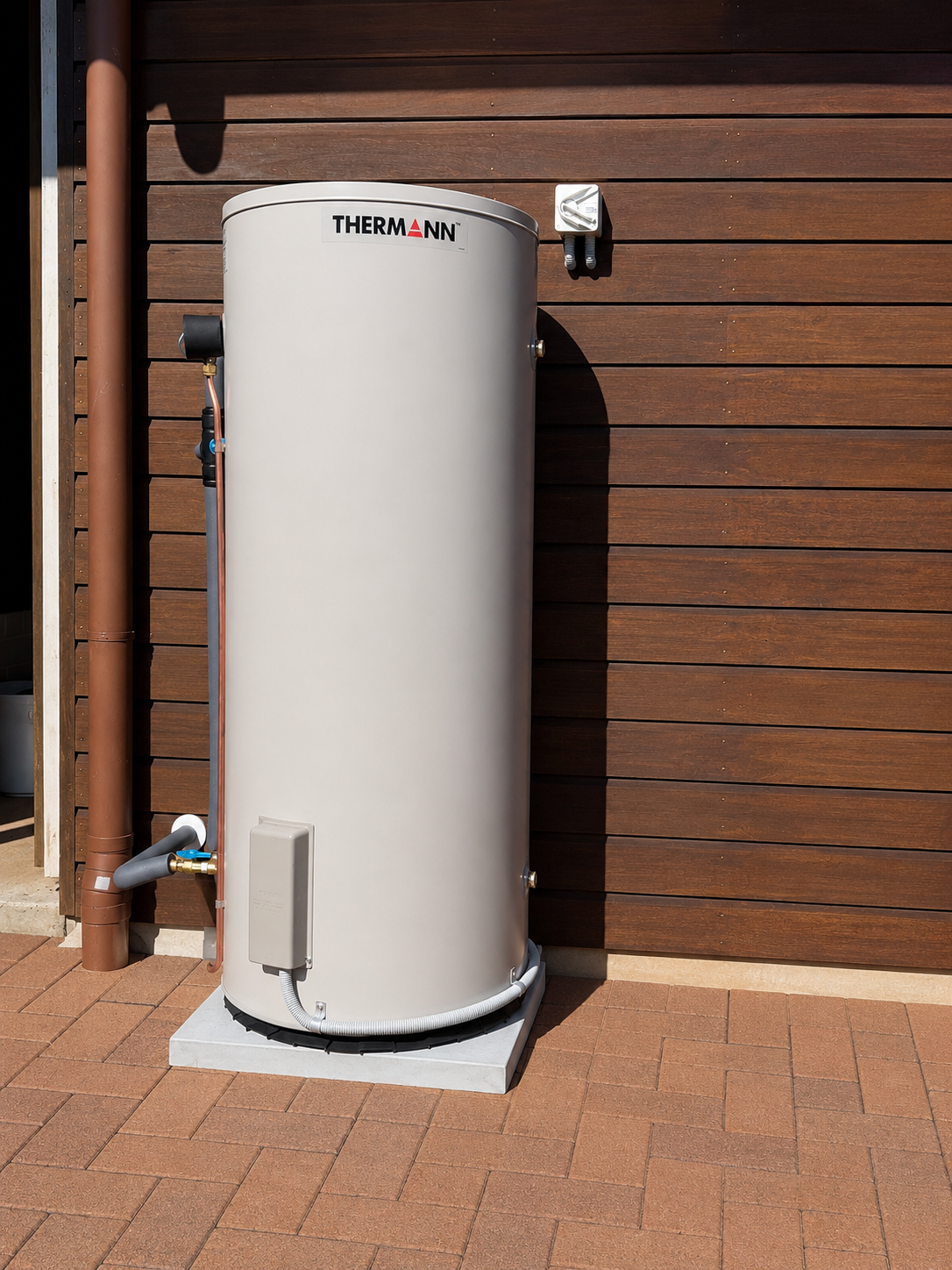 Electric hot water storage tank installed against a timber-clad exterior wall
